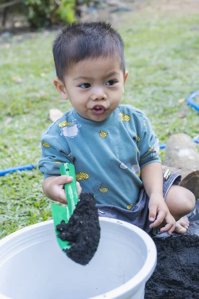 stock image Little child shovels soil into pots to prepare plants for planting. Toddler boy digging soil for planting to Mother's little helper. Gardening. Hobbies at home horticulture. Leisure activities concept