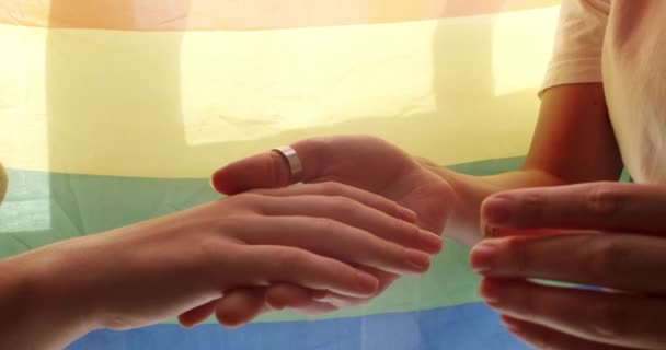女の子は恋人たちの手に婚約指輪をつけていて Lgbtの旗でロマンチックなお祝いを楽しんでいました 愛を分かち合い 手をつなぐふたりの女性 ライフスタイルと関係 Lgbtの概念 — ストック動画