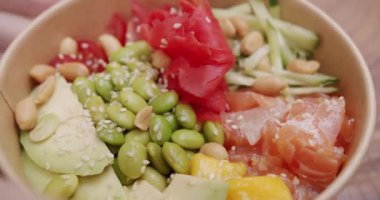 Organik ve temiz yemek. Diyet öğle yemeğinde taze balık ve sebze. Japon yemeği, somon, pirinç, avokado, edamame fasulyesi, ahşap zemin üzerinde salatalık. Sağlıklı yemek, keto diyeti konsepti.