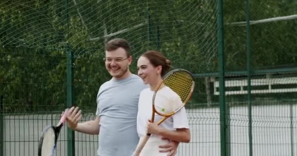 周末和周日的娱乐活动 和朋友一起积极参加体育活动 赛后网球选手 朋友们在笑 玩得开心 成功的比赛之后 夫妻二人在网球场上散步 — 图库视频影像