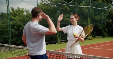 Arkadaşlar dışarıda halı kortunda tenis oynarlar. Bir kadın ve bir erkek birbirlerini selamlar ve maçın başında eğlenirler. Profesyonel tenis oynuyor. Tenis oyuncuları iş başında. Tenis maçı.