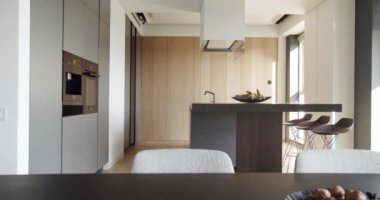Minimalist yemek masası olan modern mutfak odası. Modern lavabosu olan yerli mutfak. Mutfağın içi çok şık. Minimalist mutfak odası beyaz renklerde ve yemek alanı da doğal ahşap.
