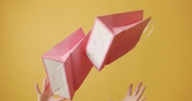 Alışveriş mi yoksa seçim kavramları mı? Kadınların elleri, izole edilmiş sarı arka planda pembe kağıt alışveriş torbaları gösteriyor. Alışveriş ve Poşetlerden gelen memnuniyet. 