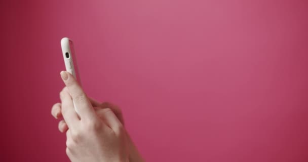 Nők Kezei Fehér Smartphone Használnak Elszigetelt Rózsaszín Háttérrel Bannerre Sms — Stock videók