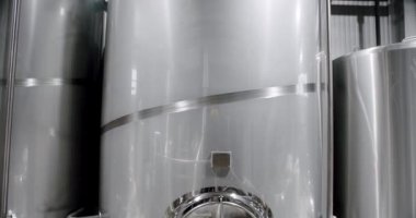 Stainless steel tanks for brewing beer. Huge stainless vats in a brewery. Equipment for beer fermentation. Brewing equipment. Factory, brewery concept. Modern brewery.