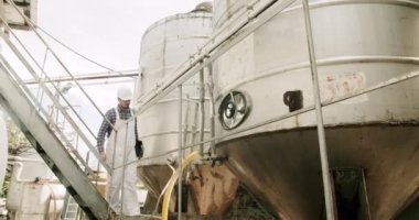 Şarap fabrikasındaki üretim ekipmanlarının kalitesini kontrol ediyor. Modern şarap üretim tesisi. Çelik şarap damıtma tankları. Şarap imalatçısı şarap fabrikasında damıtma ve fermantasyon için ekipman arıyor..