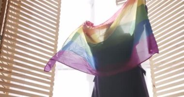 Lgbt kadınları gururlu gökkuşağı bayrağıyla evde dinleniyor. Sarıl ve tut. cinsel çeşitlilik, LGBTQI, Gurur Etkinliği, LGBT Onur Ayı, lezbiyen mutlu bayan portresi. LGBT hakları, lezbiyen ailesi. LGBT kavramı
