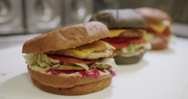 肉パテとバーガー トマト キュウリ レタス 肉カツの大きな食欲をそそるバーガー プロのレストランキッチンで料理を作る おいしいファーストフードのコンセプト — ストック動画