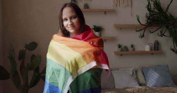 小さな女性は自慢の虹の旗を持って自宅で休んでいます 抱擁と保持 性的多様性 Lgbtqi プライドイベント Lgbtプライド月間 レズビアン幸せな女性の肖像画 Lgbtの権利 レズビアンの家族 Lgbtの概念 — ストック動画