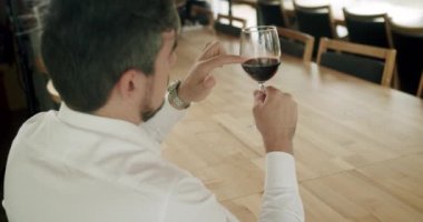 Şarap üreticisi şarap tadıyor. Camın dönüşü şarabın yüzeyini dalgalandırıyor ve uzun cam duvarlar boyunca uzanıyor. Sommelier şarap kadehini sallıyor ve tadına bakıyor..