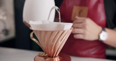 Önlüklü tanınmayan bir erkek barista modern kafede kahve hazırlarken çaydanlıktan fincana su dolduruyor. Barista özel kahve dükkanında latte yapıyor..