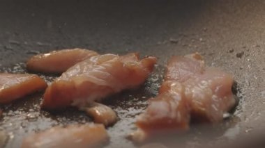 Tavada cızırdayan tavuk göğsü parçaları. Yakından çekilen çiğ tavuk göğsü parçaları dökme demir tavada sebze yağında kızartılıyor.