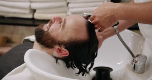 美容院的一位魅力男子被理发师招待 在一家豪华美容院的专业洗澡间里用洗发水洗头 美容院服务 — 图库视频影像