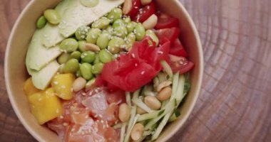 Organik ve temiz yemek. Diyet öğle yemeğinde taze balık ve sebze. Japon yemeği, somon, pirinç, avokado, edamame fasulyesi, ahşap zemin üzerinde salatalık. Sağlıklı yemek, keto diyeti konsepti.