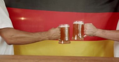 Young Peoples hands clash like glasses full of beer against the background of Germany. Soccer fans celebrating victory of team in sports bar. Friends in a Pub. Word Cup Supporters.