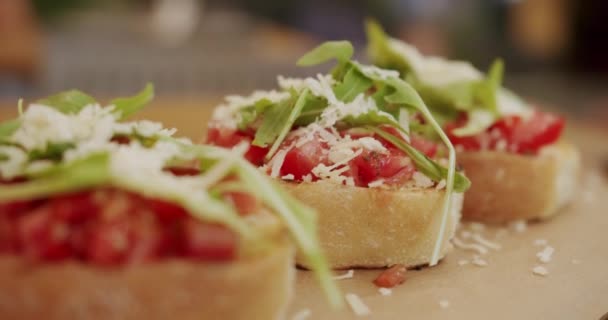イタリアのブルスケッタ クロスティーニ 健康的でビーガンフード チェリートマト チーズ アルグラとおいしいブルスケッタソース生地トースト レストランでの伝統的なイタリアの朝食ブランチ料理 — ストック動画