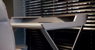 Kapatın ve rahat çalışma odasındaki minimalist deri sandalyeli modern masayı detaylandırın. Oda palmiyesi dekoru. Minimalist siyah panjurlar. Güzellik odasındaki aksesuar. Deri koltuklu ve masalı..