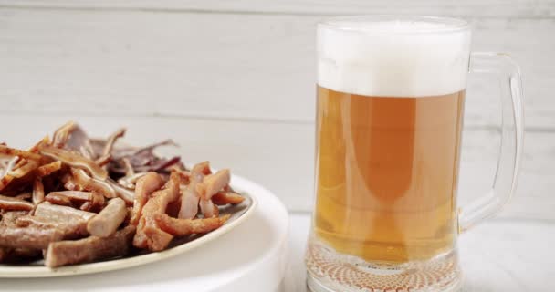 把啤酒放在大玻璃杯里 啤酒杯 啤酒杯 在白色的背景上半升 近一点 旋转360度 杯子里装满了啤酒和盘子里的切肉 还有零食 啤酒小吃用Bbq肉 — 图库视频影像