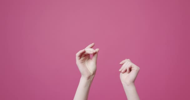 スタジオで指をスナップクロップ女性 認識できない女性の腕を上げ 明るいピンクの背景に指をスナップの静的なショット — ストック動画
