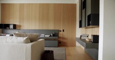 Ahşap modern kapısı olan lüks şık bir oda. Ahşap duvarlı ve gri mobilyalı modern Minimalist oturma odası. Gri kitaplıklı lüks Modern Ev İçi. Modern raflar ve kitap.
