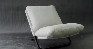 Modern izole gri arka planda beyaz kumaş minimalist sandalye. Evdeki modern beyaz sandalyenin iç dekorasyonunun kamyon çekimi. Rahat, rahat bir sandalye. Modern, rahatlatıcı koltuğa oturmuş.