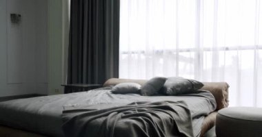 Zarif beyaz ve kahverengi iç tasarım. Minimalist beyaz yatak odası. Modern Hotel Yatak Odası İçi ve Yastıklı Yatak. İçi beyaz duvarlarda raflarla dolu. Mobilyalı lüks yatak odası.