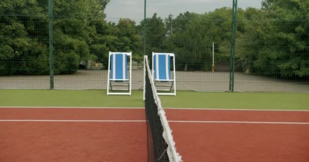 レクリエーションのためのメッシュと椅子で屋外カーペットテニスコートの一部を撮影 プロテニスをする 週末と日曜日のレクリエーション活動 テニスの試合だ アクティブレジャーゲーム — ストック動画
