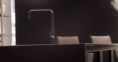 Modern ahşap mutfak mobilyaları. Zarif, rahat ve Minimalist Ev. Modern siyah lavabosu olan yerli mutfak. Minimalist yemek masası olan modern mutfak odası. Modern Minimalist Ev.