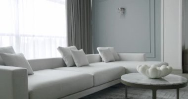 Beyaz, gri mobilyalı ve yuvarlak masalı modern Minimalist oturma odası. Köşedeki kanepe ve kitaplığı olan lüks modern ev iç mimarisi. Moda mobilyalar. Minimalist Ev İçi.