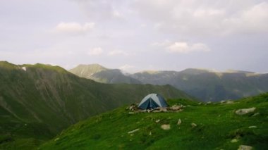Yürüyüşten sonra kamp yapıp dinleneceğiz. Doğadaki bir kişinin geri kalanı, dağlarda. Dağ tepelerinde çadır. Bahar dağlarında çadırına yakın bir turist. Gün batımında dağ tepeleri