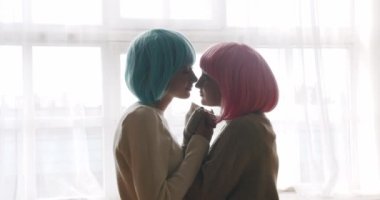 Couple, lgbt and lesbian women at home. Embrace and holding each other. Love and kiss, Low angle handheld shot of young lesbian couple smiling and touching hands gently. LGBT rights, Lesbian family.