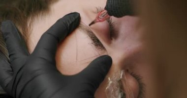 Microblading, permanent makeup tattoo close up. Master makes permanent eyebrow makeup procedure using special needle tattoo machine to woman in beauty salon. Microblading brows tattooing.