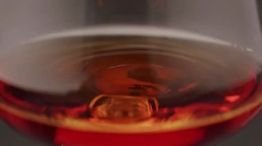 Luxury brandy and drop in glass of cognac. Glass with golden cognac on isolated black background with smoke. Brandy, cognac, and whisky. Slow motion. Luxury Drink Whisky with smoke.