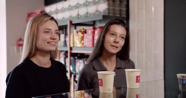 作物認識できないバリスタは クレジットカードで非接触を支払い カフェで笑顔明るい若い女性のクライアントにテイクアウトコーヒーの紙コップを与える — ストック動画