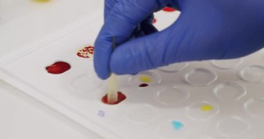 Crop doctor mixing blood with chemicals. From above closeup handheld shot of anonymous medical specialist in latex gloves mixing blood samples with reagents during work in clinic lab.