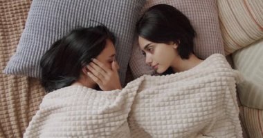 Couple of women hug each other warmly and relax at home in the bedroom. Lgbt and lesbian women at home. Embrace and holding each other. Friendship concept. Lifestyle and relationships.