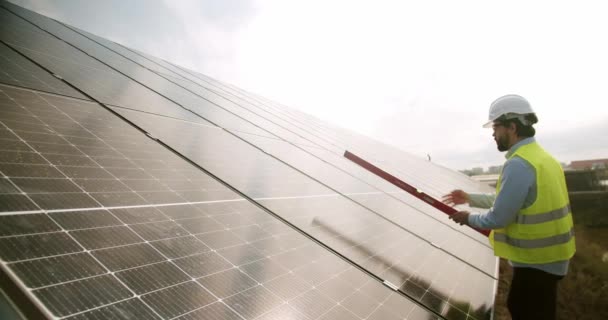 太陽光発電所に太陽光発電パネルを設置する制服とハードハットの労働者 若いエンジニアは 新しい日当たりの良いバッテリーをインストールします 緑のエネルギーの概念 — ストック動画