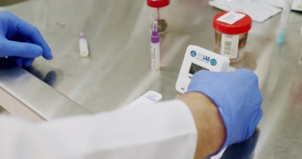科学家使用微管在现代实验室的试管中混合液体 在医疗实验室工作时 身穿白色长袍 戴着手套和眼镜的男人把装有样品的小瓶放进机器 — 图库视频影像