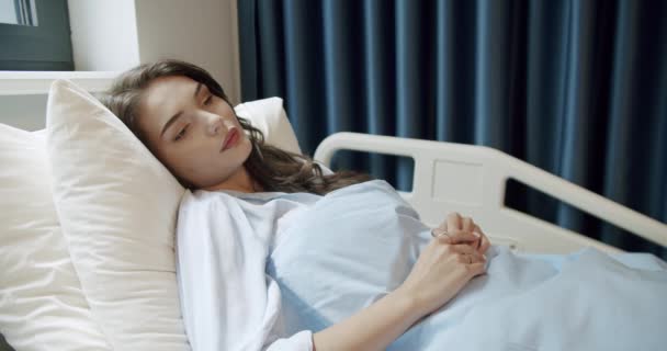 潘在医院的轻病房里 看到一个黑头发的年轻病人舒服地躺在靠窗的床上 卧床病房女病人 住院女病人 — 图库视频影像