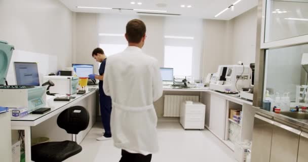 在诊所实验室工作的男人现代医院实验室工作中穿着制服 准备样品 使用分析仪器的男性医学专家手持照相 — 图库视频影像