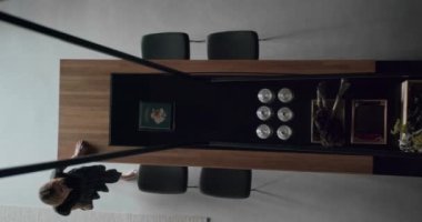 The woman sits on chair in modern and spacious wooden kitchen room. Real Estate. Top view. Luxury kitchen with wooden island and chairs. Modern interior in luxury house.