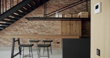 Modern and spacious wooden kitchen room with wall bricks and black staircase. Real Estate. Minimalist design in New Home. Real Luxury Design Interior. Neoclassic Style, cozy interior.