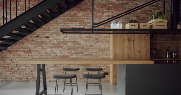 现代宽敞的木制厨房 有墙砖和黑色楼梯 房地产 豪华厨房 有木制岛屿和椅子 豪华住宅的现代室内装饰 新家的简约设计 — 图库视频影像