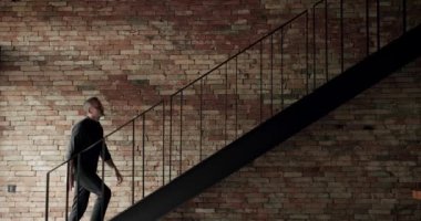 The man was climbing the stairs in the house to the second floor of the house. The man descends the stairs in the house from the second floor in the house. textured surface of stucco texture