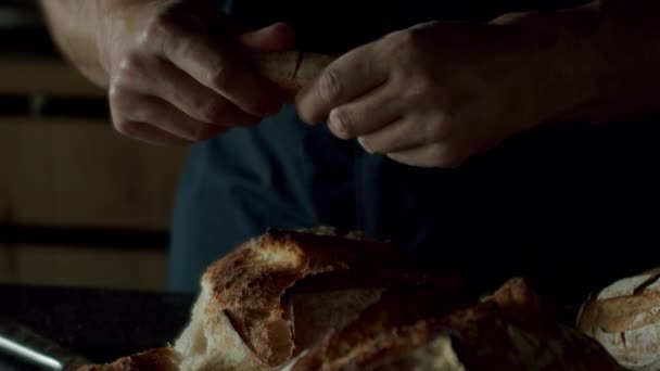 现代木制厨房里穿着黑色衬衫的人慢吞吞地把面包吃在桌上 房地产 豪华厨房 现代室内装潢和有木墙的餐厅 — 图库视频影像