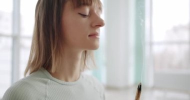 Woman meditating with Palo Santo, holy wood, Bursera Graveolens , relaxation zen practice in studio, herbal healing, yoga or aura cleaning. Essential incense for esoteric rituals, 