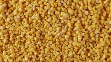 Top view of a surface filled with many ripe corn kernels. zoom and slow motion. Fresh corn kernels on yellow textured surface.