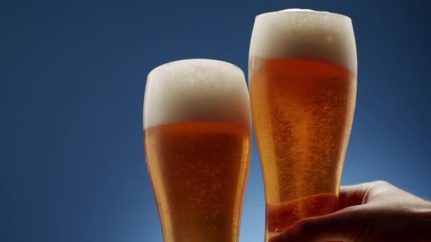 Two Glasses Full Frothy Beer Collide Middle Blue Background Foam — 图库视频影像