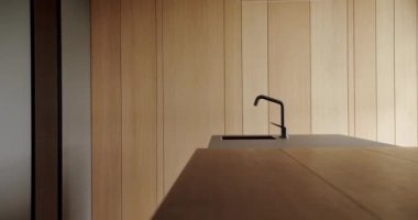 Real kitchen with an island. Modern interior in luxury house. Interior of a minimalist kitchen. Light Wood Wall and Floors. Modern kitchen and bar brown chairs in kitchen room in minimalist apartment.