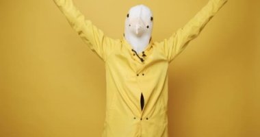 Fun and happiness concept. Funny Guy in Yellow Suits Dance with Pigeon Mask, Man having fun on isolated Yellow Background. Having Fun, Party Halloween. Fools Day. Masquarade idea.